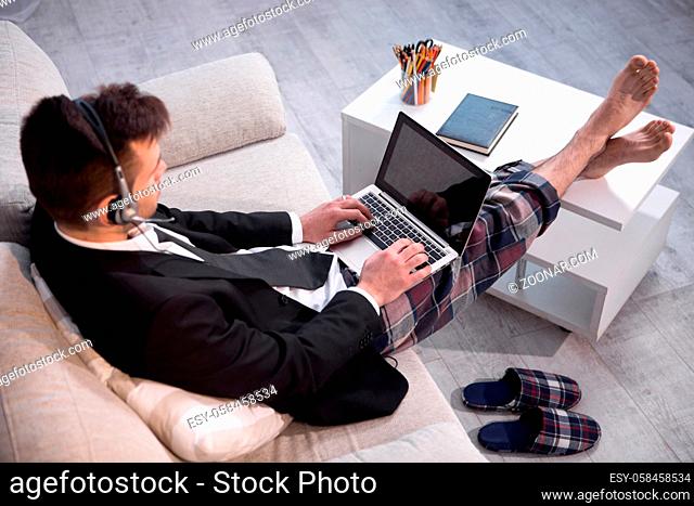 Man typing on laptop working on freelance at home. Up view on a man in casual trousers and jacket keyboarding on computer