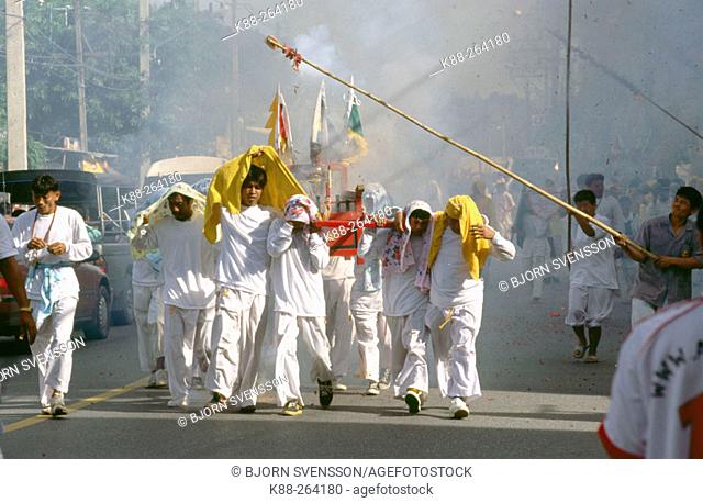 Firecrackers are thrown at religious procession to scare away evil spirits during the Vegetarian Festival. Phuket. South Thailand