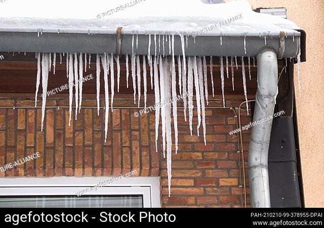 10 February 2021, Lower Saxony, Peine: Long icicles hang from the roof of a house. Photo: Julian Stratenschulte/dpa. - Peine/Lower Saxony/Germany