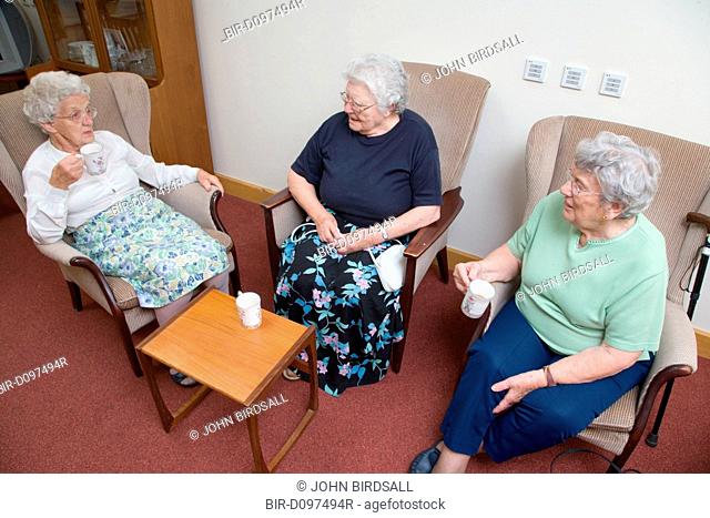 A group of older ladies enjoying a coffee morning in the communal lounge of a warden aided home