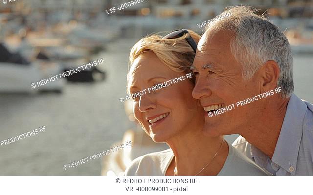 head and shoulders shot of senior couple sitting together by marina in sunset