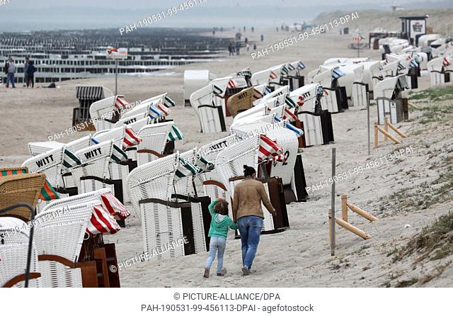 31 May 2019, Mecklenburg-Western Pomerania, Graal-Müritz: Empty beach chairs stand in a row at the beach, only few visitors are on the way at the coast