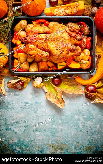 Roasted whole chicken or turkey with pumpkins, pepper and potatoes. With colorful mini pumpkins, autumn leafs and chestnuts served around aged stone dark rustic...