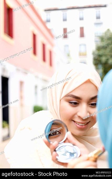 Young woman applying make-up on female friend