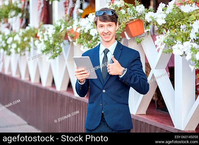 young man in business suit holding tablet on summertime day