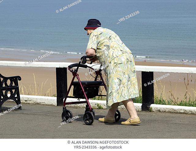 Elderly lady with Rolling walker, on upper promenade at Saltburn by the Sea, North Yorkshire, England, United Kingdom