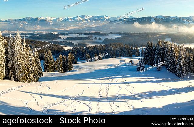 Amazing Panoramic View from Snow Mountain with Trees and Ski trails to snowy and foggy Mountain Ranges. Mountain Hut Klings Huette on Hauchenberg near Diepolz...