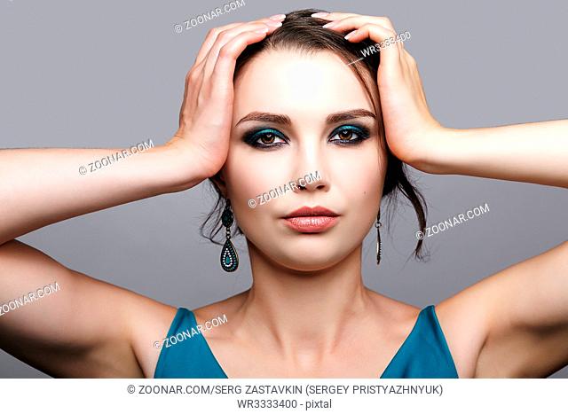 Portrait of young brunette woman on gray background. Female beauty makeup concept