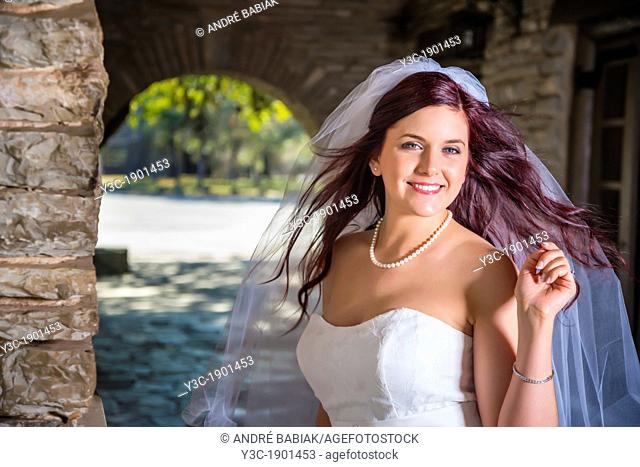 Bridal portrait - A young bride in wedding dress posing at historical looking building at Garner State Park, Concan, Texas, USA, Female Caucasian, 23 years old