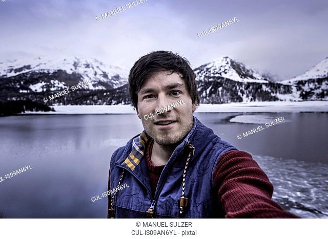 Male hiker taking selfie at lake Silsersee, Malojapass, Graubunden, Switzerland