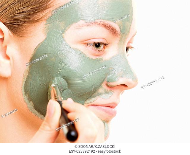 Woman applying with brush clay mud mask her face
