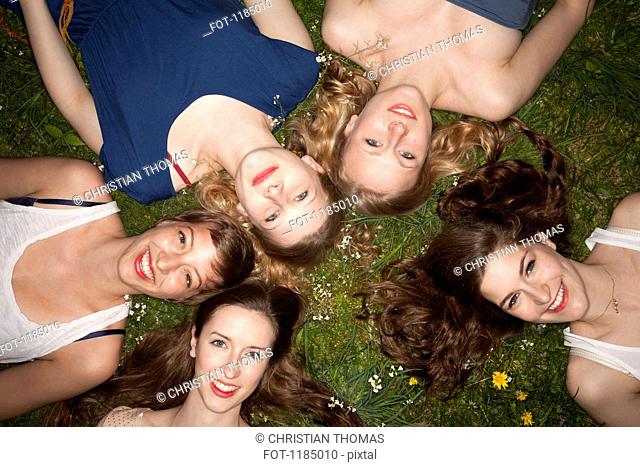 Five cheerful female friends lying in the grass, head and shoulders