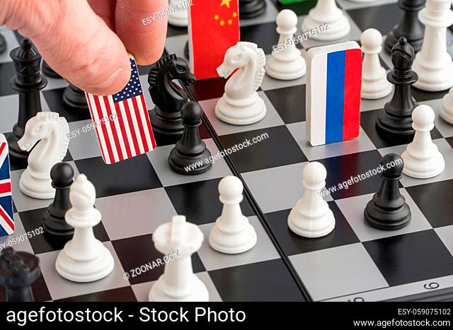 Politician's hand moves a chess piece with a flag. Conceptual photo of a political game. retaliatory move USA
