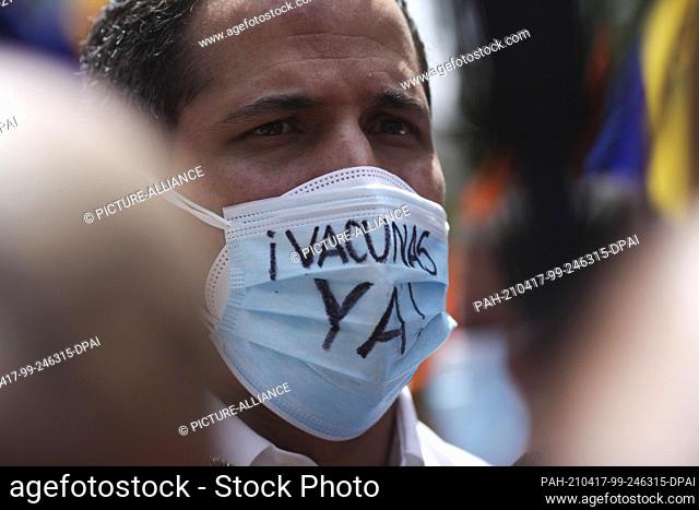 17 April 2020, Venezuela, Caracas: Juan Guaido, self-proclaimed interim president, wears a mouth guard with the words ""Vaccines Now"" as he participates in a...