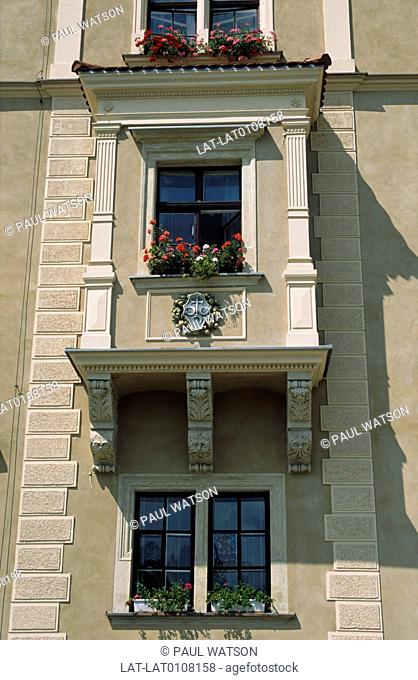 The Wawel. Royal citadel. Historic house front. Carving on balustrade. Coat of arms. Flowering plants
