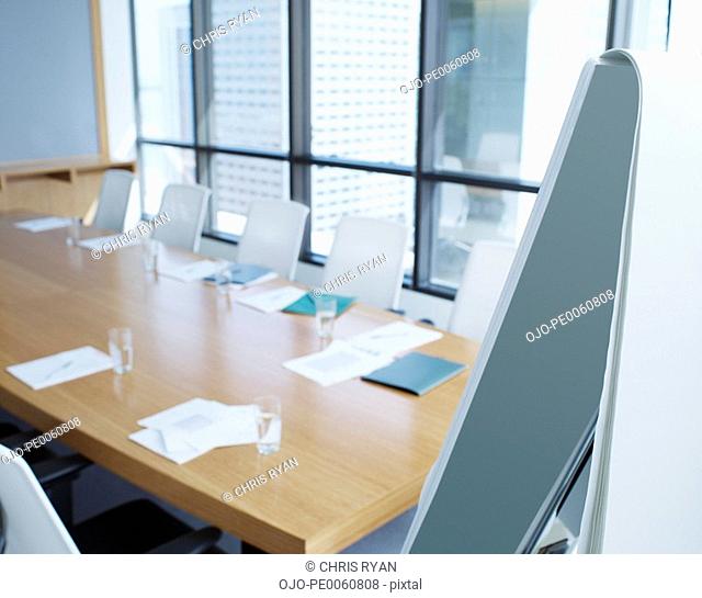 Empty boardroom with folders on table and easel in foreground