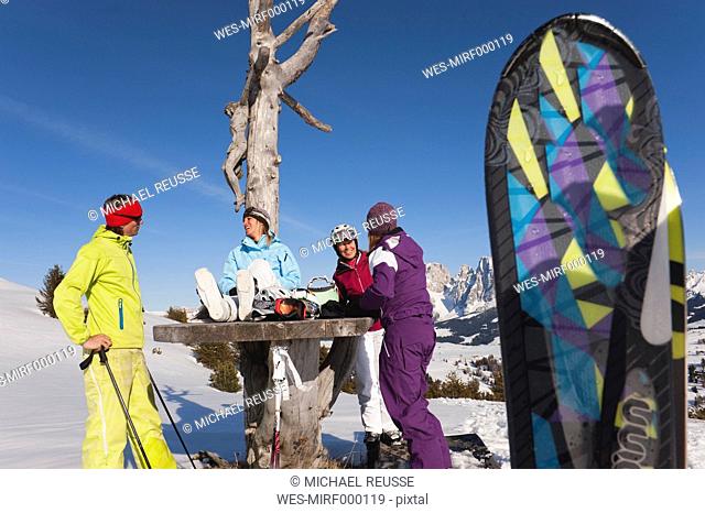 Italy, Trentino-Alto Adige, Alto Adige, Bolzano, Seiser Alm, People with skiing equipments resting near bare tree on snowy landscape