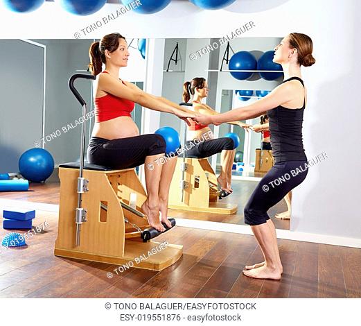 pregnant woman pilates leg pumps exercise on wunda chair with personal trainer