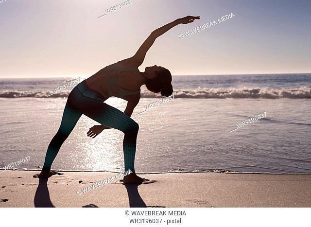 Woman performing stretching exercise in the beach