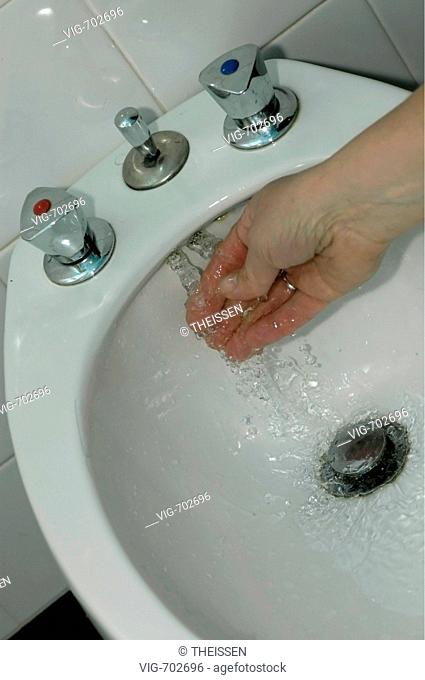 hand testing running water in an oldfashioned bidet in a bathroom. - 05/04/2006