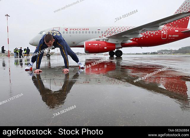 RUSSIA, SOCHI - APRIL 6, 2023: Strongman Denis Vovk warms up before pulling a Rossiya Airlines Sukhoi SuperJet 100 passenger aircraft using a rope at the Sochi...