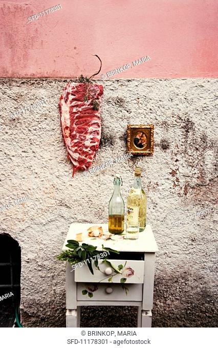 Raw pork ribs hanging on the wall of a house, next to a a gold-framed picture
