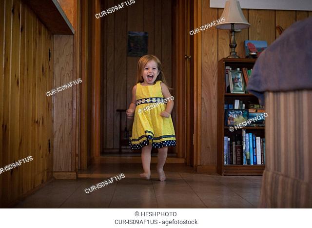 Female toddler running barefoot over wooden floor