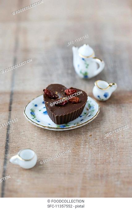 A praline with dried barberries on a porcelain doll's plate