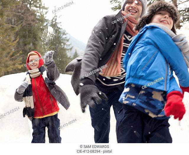 Father and sons enjoying snowball fight