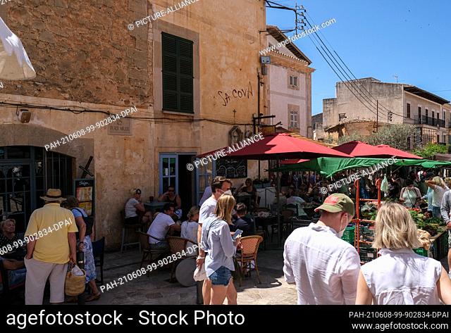 29 May 2021, Spain, Santanyi: Holidaymakers sit at the tables of cafes and restaurants on market day in Santanyi. In the foreground the restaurant Sa Cova Bar y...