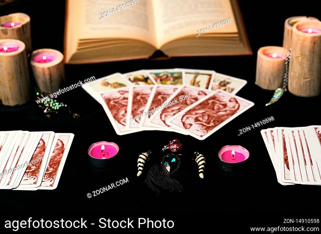 Candles and old tarot cards on black silk. Halloween and fortune telling concept. Mystic background with occult and magic objects on witch table