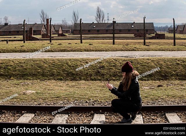 Tourist making a photo on the Railway leading to main entrance of Auschwitz Birkenau concentration camp, Poland March 12, 2019 war