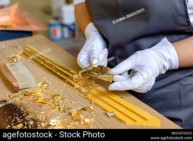 Mature woman decorating frame while standing at workbench in workshop