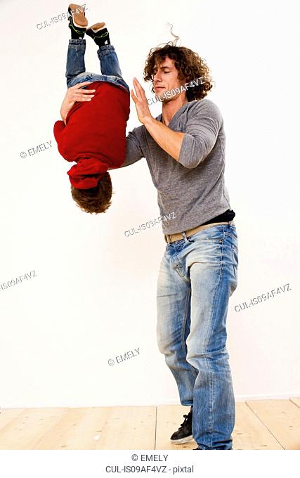 Studio shot of father turning over son in mid air