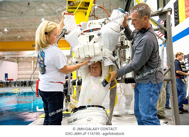 European Space Agency astronaut Timothy Peake gets help donning a training version of his Extravehicular Mobility Unit (EMU) spacesuit in preparation for a...