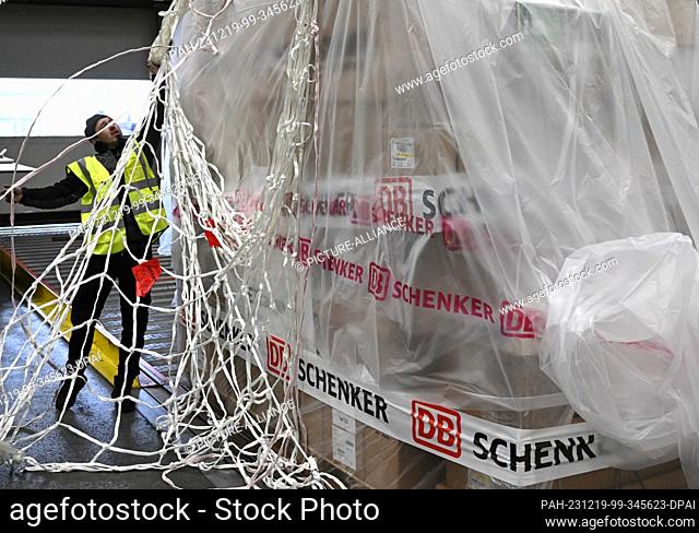 PRODUCTION - 07 December 2023, Hesse, Frankfurt/Main: A DB Schenker Jetcargo employee attaches a net to a pallet of freight in the logistics company's air...