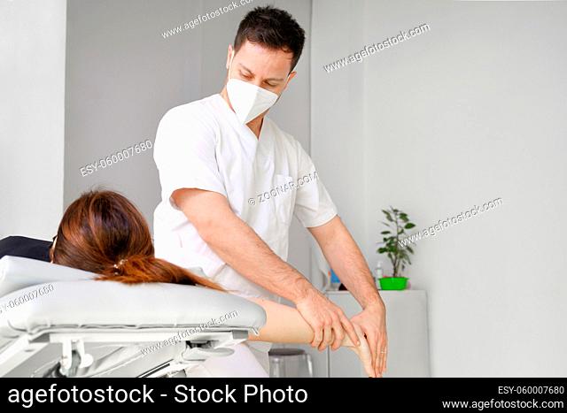 Male therapist giving massage to relief shoulder pain to a female patient in physiotheraphy clinic. High quality photo