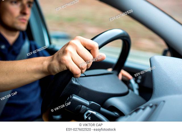 Male driver's hands driving a car on a highway (color toned image; shallow DOF)