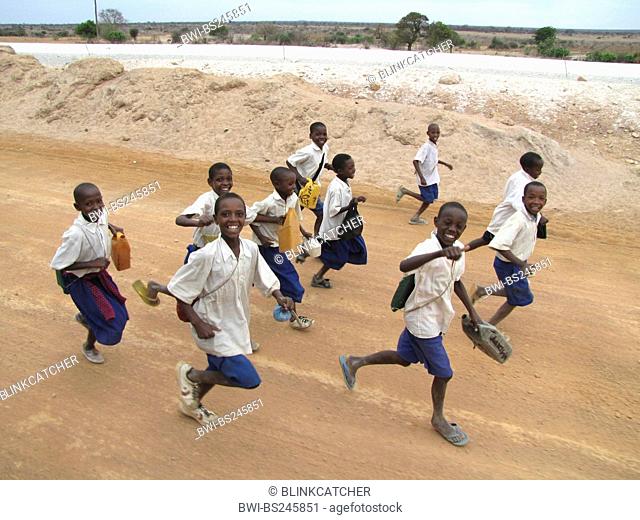 children in school uniforms running on unpaved road with a smile near the administrative capital, Tanzania, Dodoma, Dodoma