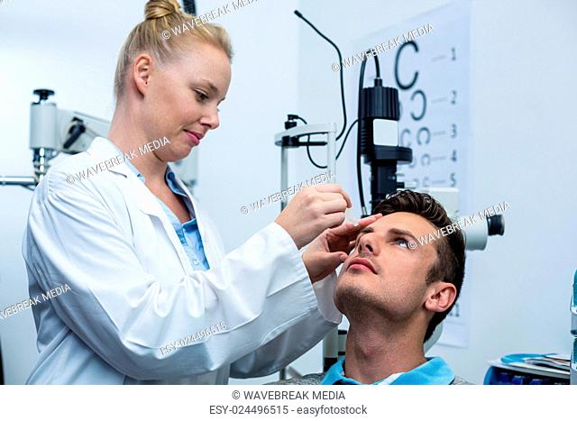 Female optometrist putting eye drop in patient eyes