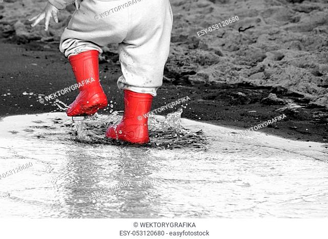 wellingtons in puddle. kid rubber boots in the sea background