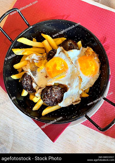 Fried eggs with morcilla and fried potatoes. Spain