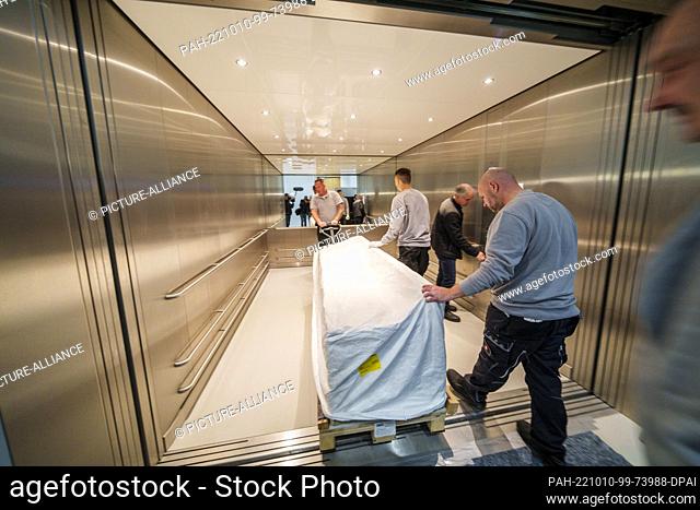 PRODUCTION - 10 October 2022, Rhineland-Palatinate, Mainz: Employees of the transport company push a copy of a Roman sarcophagus (3rd-4th century BC) into the...