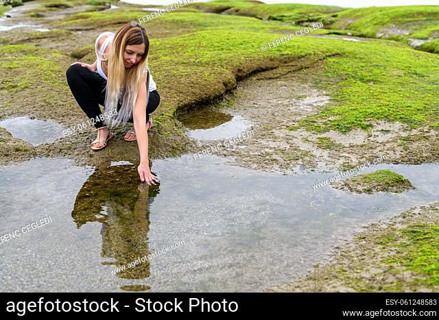 People exploring the intertidal zone of Vancouver, British Columbia. Those rocks are underwater at high tide, and out of water at low tide and revealing a...