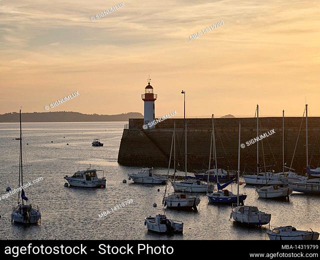 The boat harbor and lighthouse in Erquy at the golden hour in the department of Côtes-d'Armor in Brittany, France
