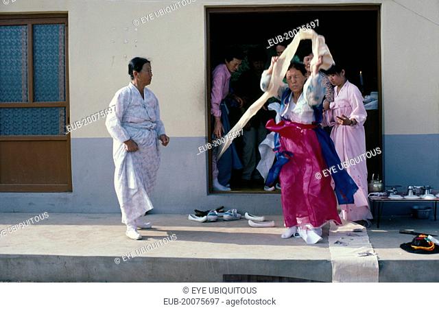 Female Shaman in a trance at a wedding waving cloth above her head with people looking on