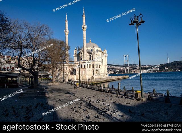12 April 2020, Turkey, Istanbul: Pigeons are on their way in front of the Bosporus Bridge and the Ortaköy Mosque during the two-day curfew imposed by the...