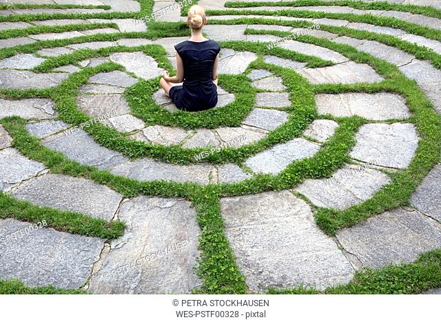 Italy, Alto Adige, Lana, woman sitting in natural open air maze meditating