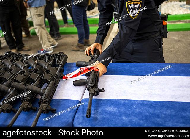 27 October 2023, Israel, Ashkelon: A police officers sorts M5 automatic assault rifles ahead of handing them to members of the new civilian guard unit during an...