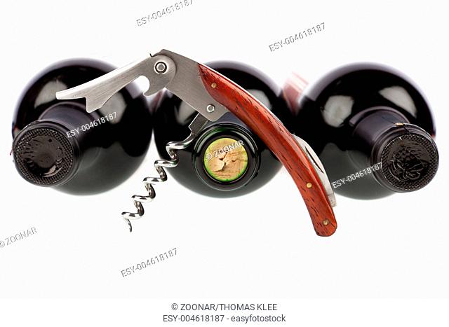 Corkscrew opened in front of a three wine bottle